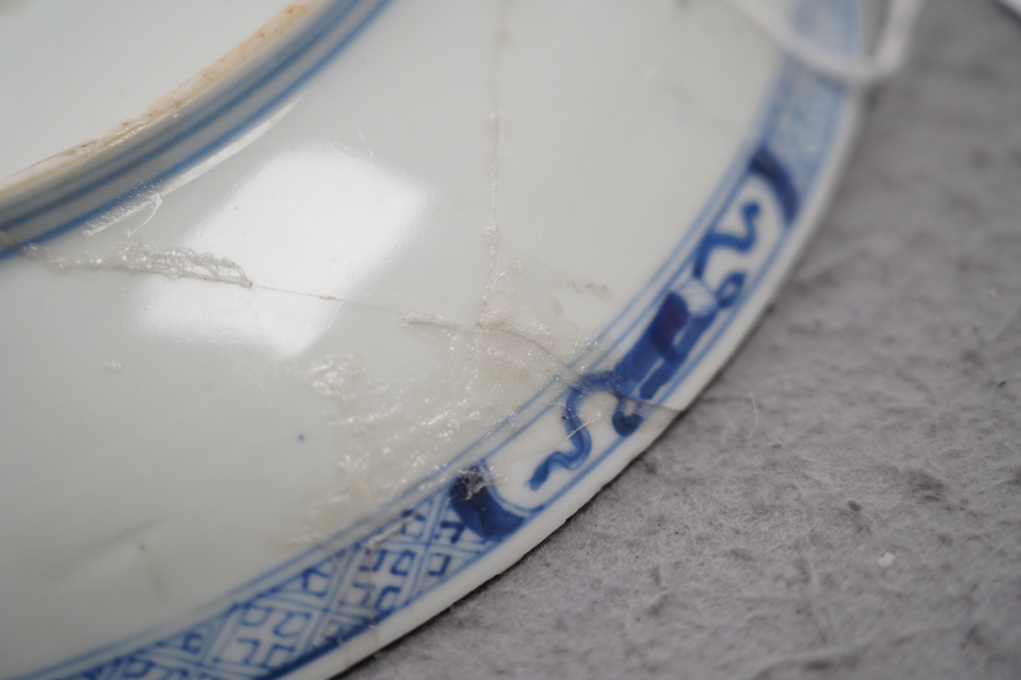 A Chinese blue and white dish, Kangxi period, broken and messily reglued